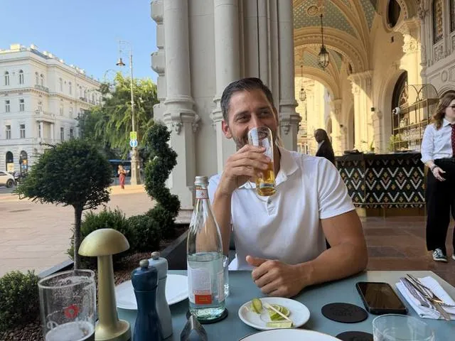 Me drinking a beer outside a grand building in Budapest