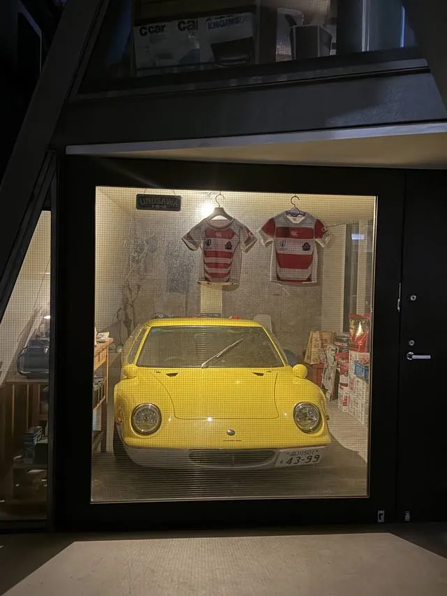 A yellow sports car displayed behind glass