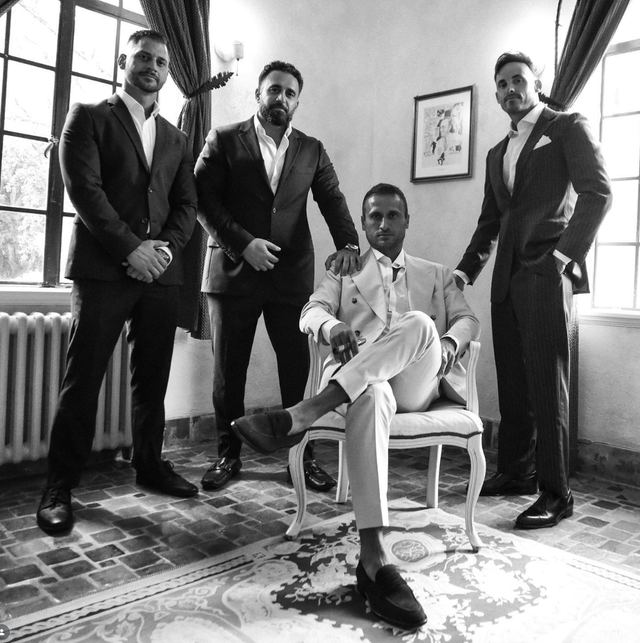 Black and white portrait of me seated in a light suit with three friends standing behind