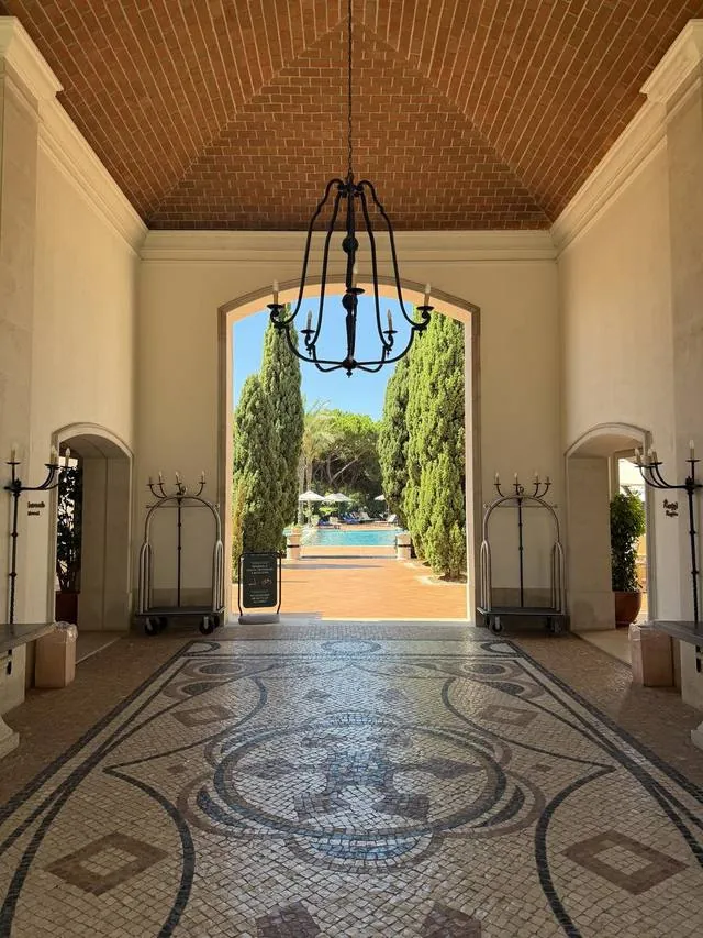 A tiled hotel lobby looking through an arch to the garden beyond