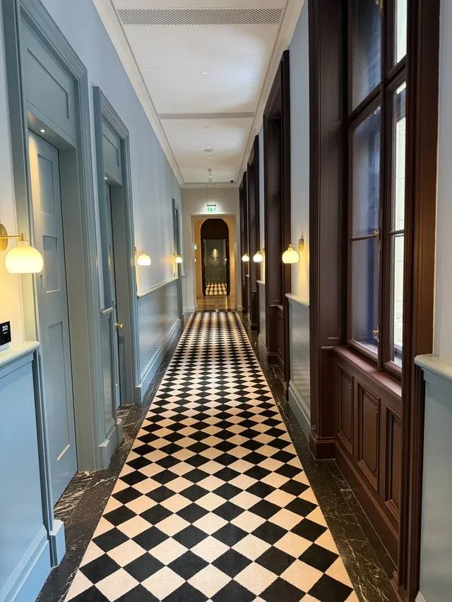 A hotel hallway with a black and white checkerboard floor