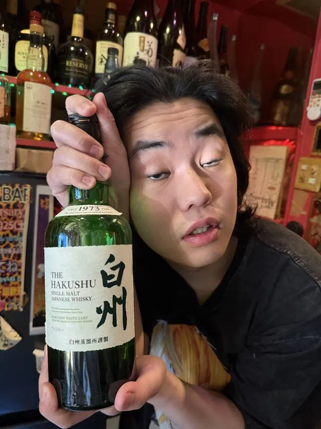 A friend holding a bottle of Hakushu single malt whisky